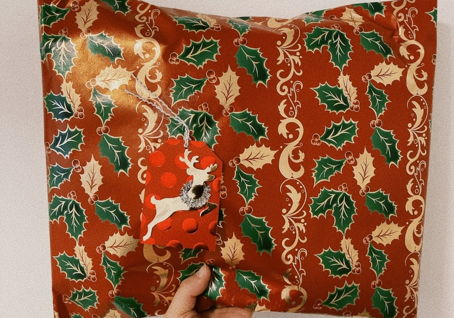 赤と緑と金色のクリスマスギフトラッピングを施されたクリスマスプレゼント。トナカイのメッセージカード付き。