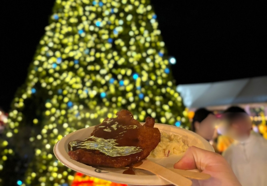 バンクーバーのクリスマスマーケットで提供されるシュニッツェル。クリスマスツリーを背景に盛り付けられている。