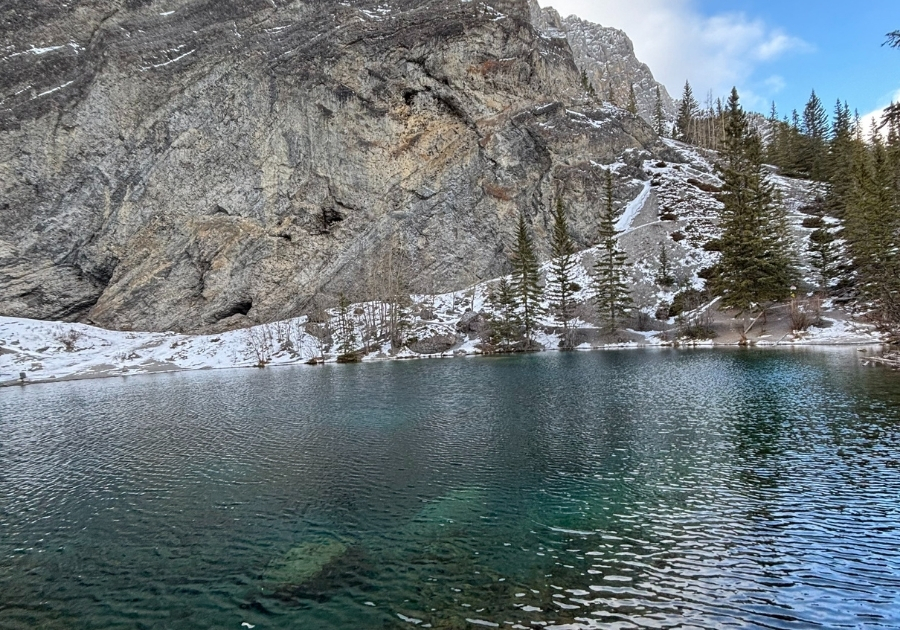 冬のGrassi Lakes。透明度の高い青緑色の湖と、雪の残る岩壁、針葉樹が並ぶ自然風景。