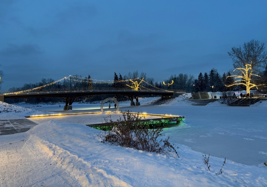 冬の夕方に撮影したカルガリーのEau Claire Park。ライトアップされた橋と雪に覆われた川沿いの風景